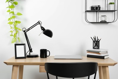 Cozy workspace with laptop, lamp and stationery on wooden desk at home