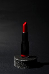 Photo of Beautiful glossy red lipstick on black background