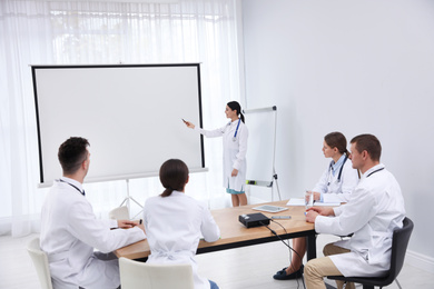 Photo of Team of doctors using video projector during conference indoors