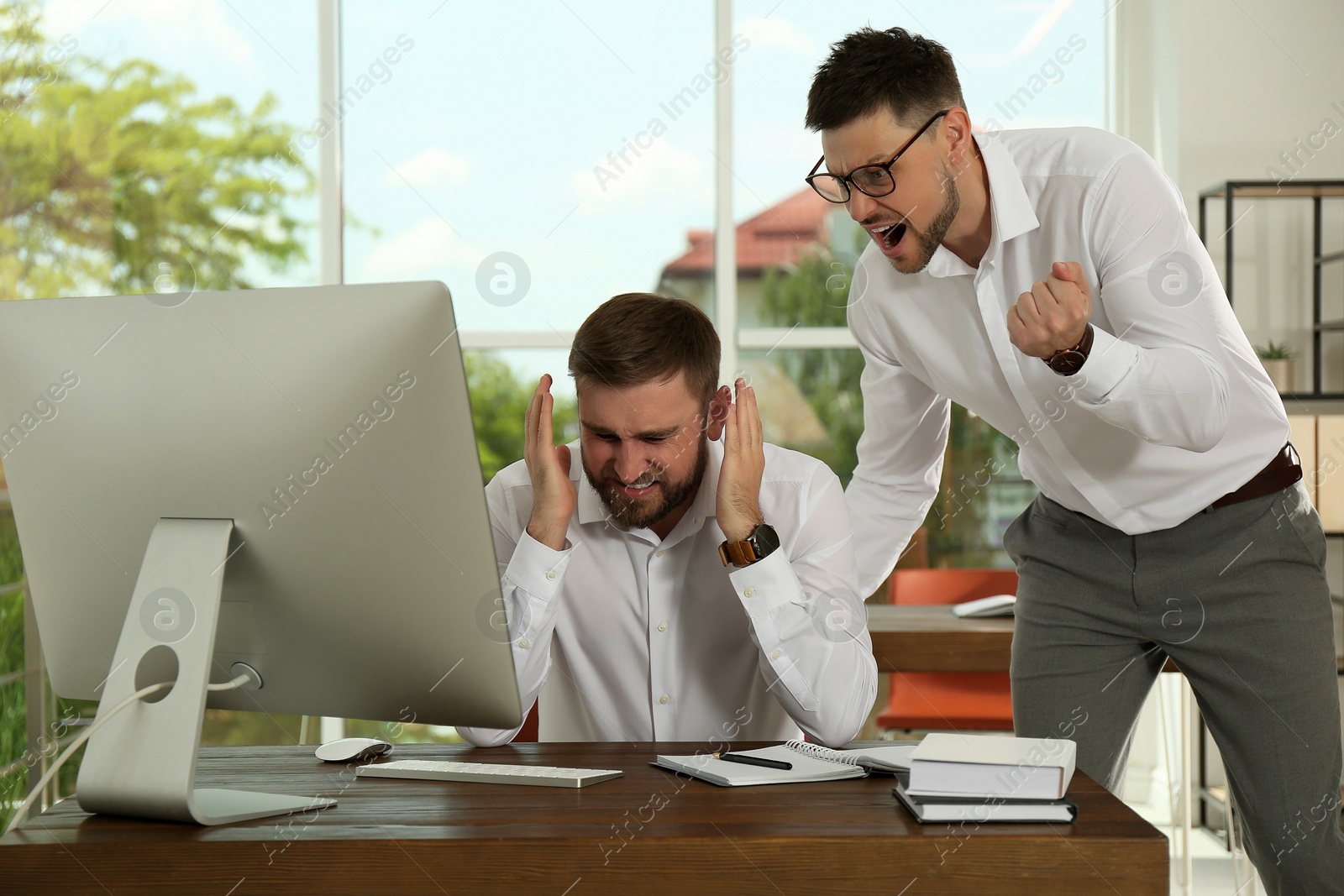 Photo of Boss screaming at employee in office. Toxic work environment