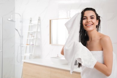 Photo of Happy young woman drying hair with towel after washing in bathroom. Space for text