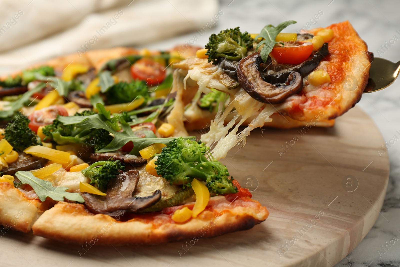 Photo of Taking piece of delicious vegetarian pizza at table, closeup