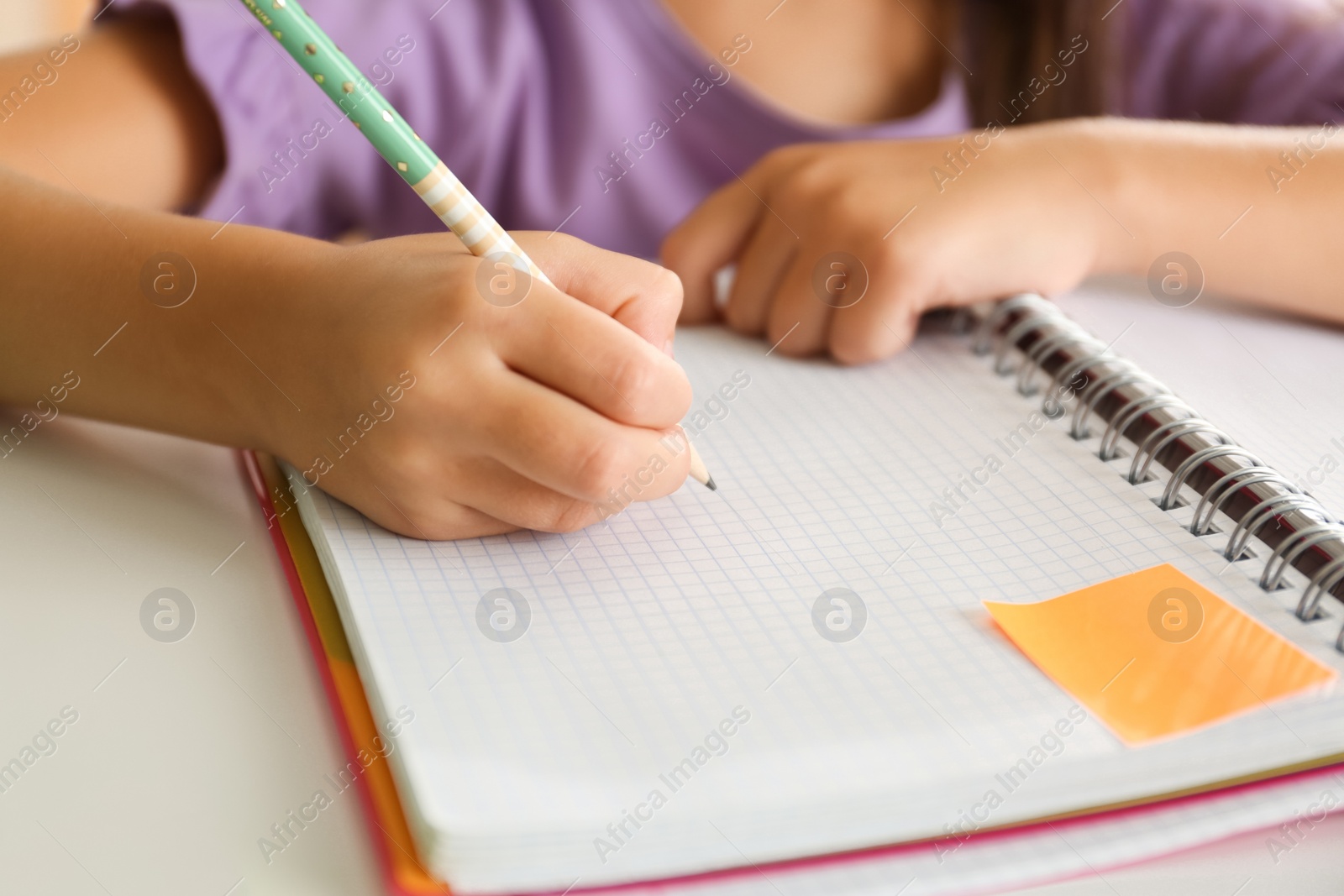 Photo of Little girl doing homework at table, closeup