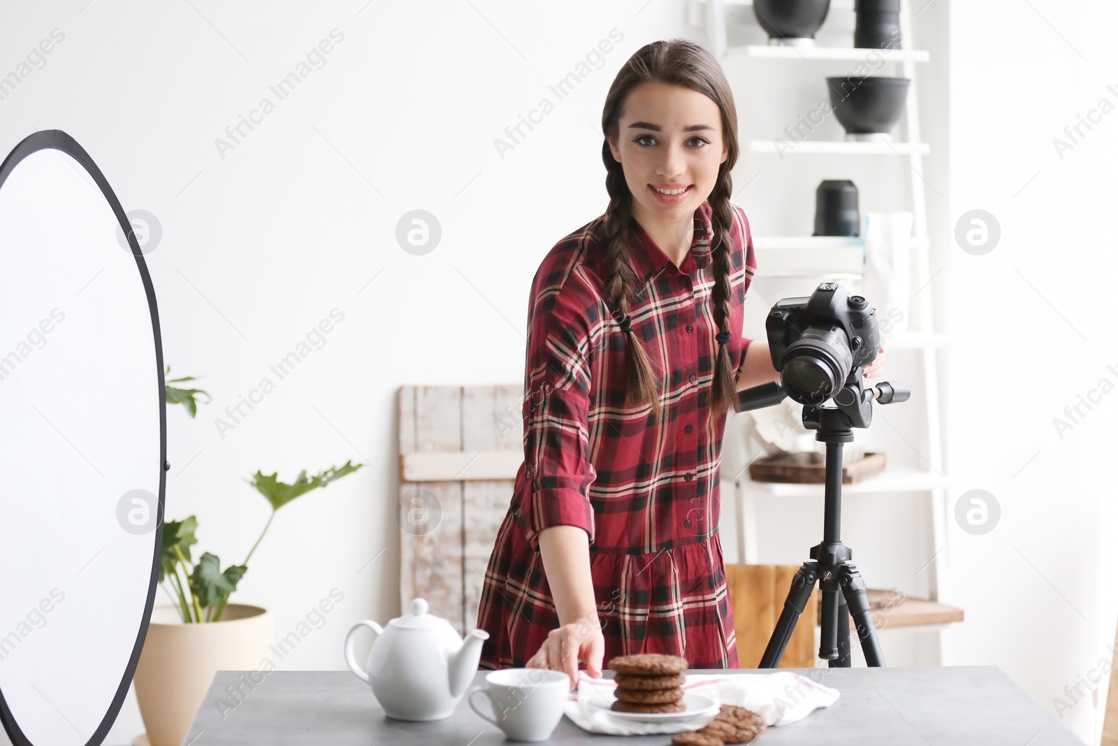 Photo of Young woman with professional camera preparing food composition in photo studio