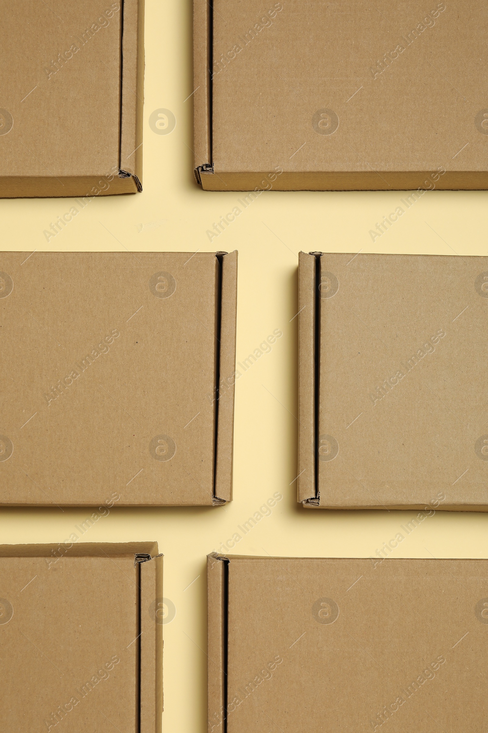 Photo of Many closed cardboard boxes on pale yellow background, flat lay