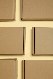 Many closed cardboard boxes on pale yellow background, flat lay