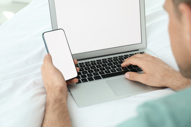 Photo of Man with smartphone and modern laptop at home, closeup