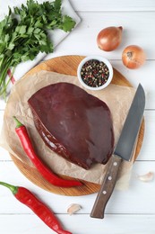 Piece of raw beef liver, knife and products on white wooden table, flat lay