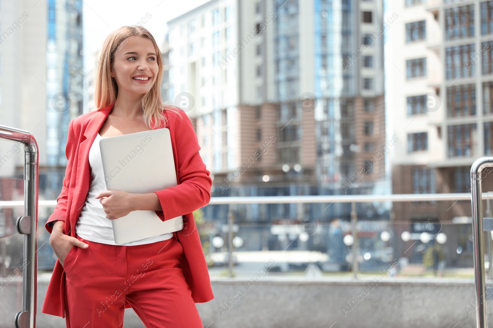 Photo of Beautiful businesswoman with laptop on city street. Space for text