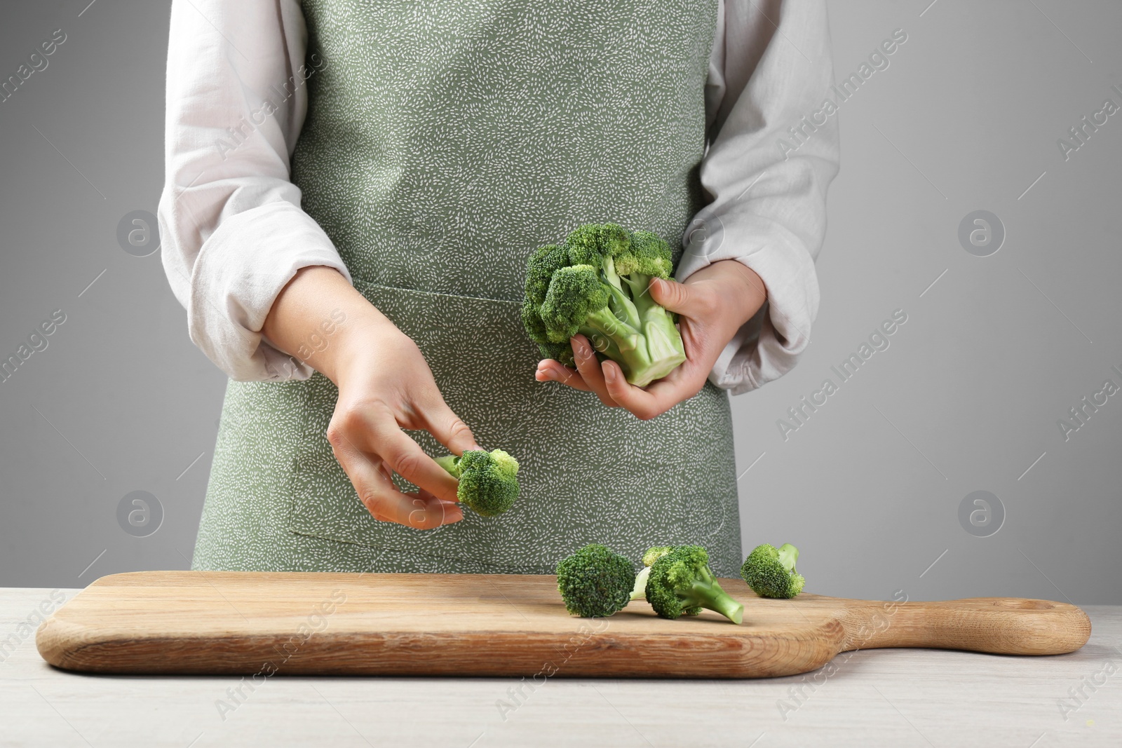 Photo of Woman with fresh broccoli at wooden table, closeup
