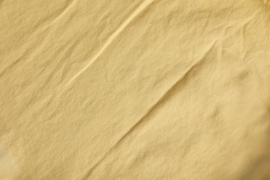 Crumpled pale yellow fabric as background, top view