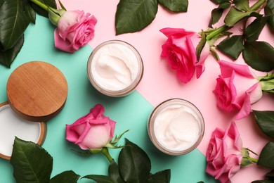 Photo of Glass jars of face cream and roses on color background, flat lay