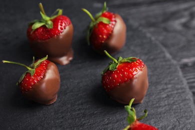 Photo of Slate plate with chocolate covered strawberries on table, closeup