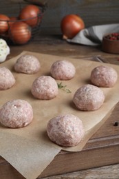 Photo of Many fresh raw meatballs on wooden board