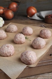 Many fresh raw meatballs on wooden board