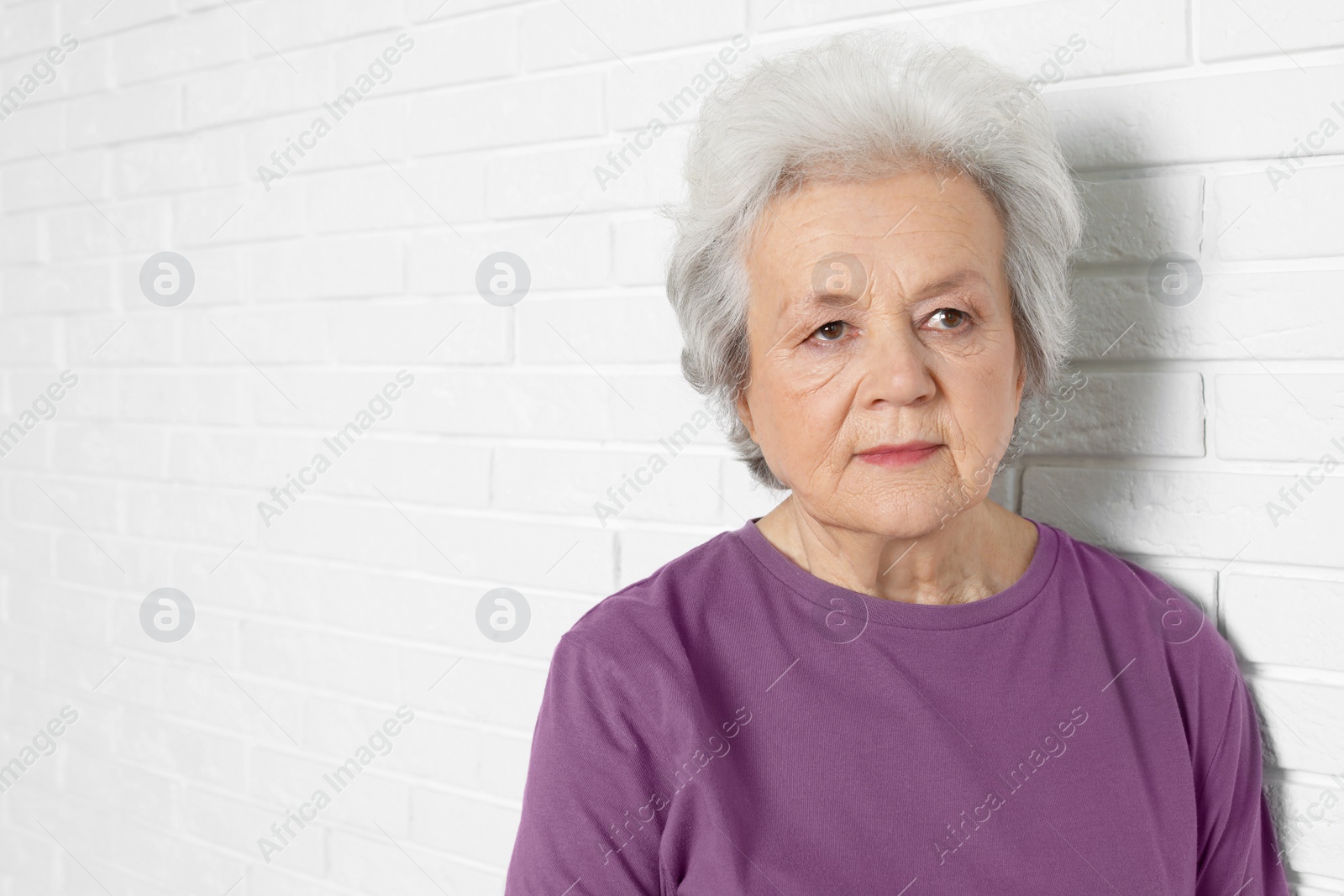 Photo of Portrait of mature woman near brick wall. Space for text