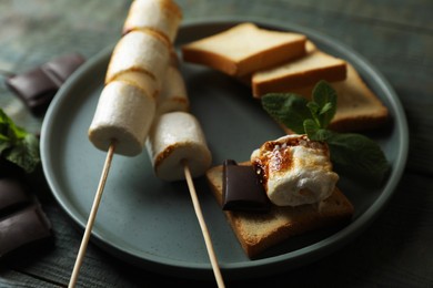 Delicious sandwich with roasted marshmallows and chocolate on grey wooden table, closeup