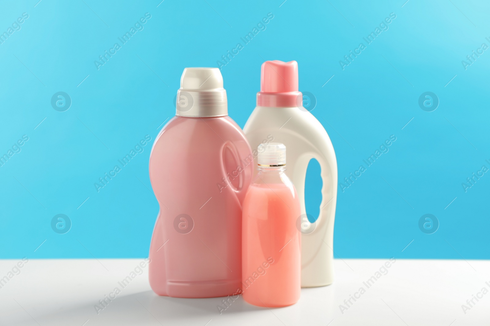 Photo of Bottles of laundry detergents on white table
