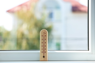 Photo of Wooden weather thermometer on window sill indoors