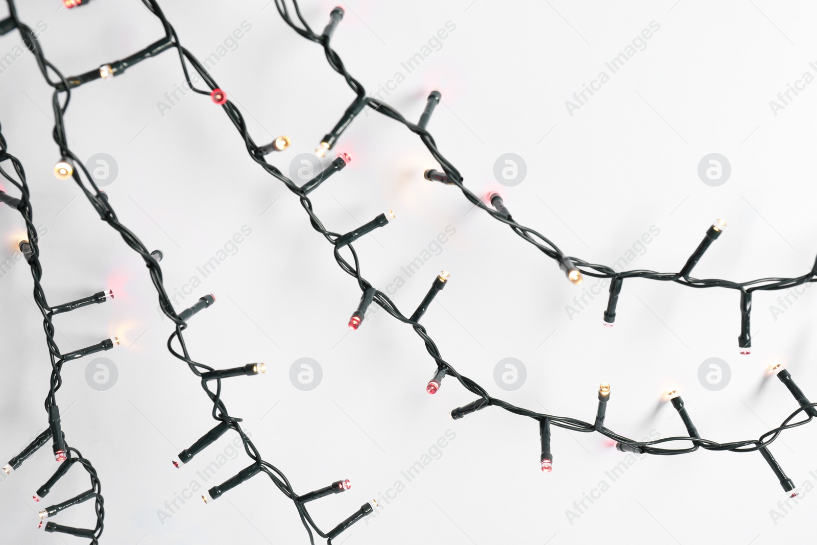 Photo of Beautiful Christmas lights on white background, top view