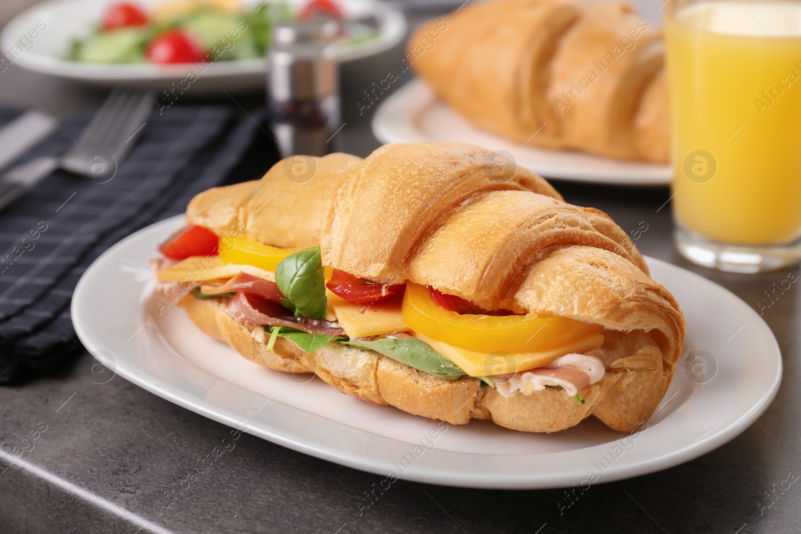 Photo of Plate with tasty croissant sandwich on table