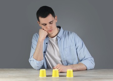 Photo of Man playing shell game at wooden table