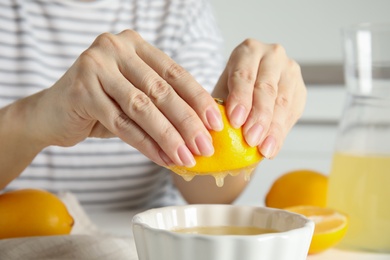 Photo of Woman squeezing lemon juice into bowl, closeup