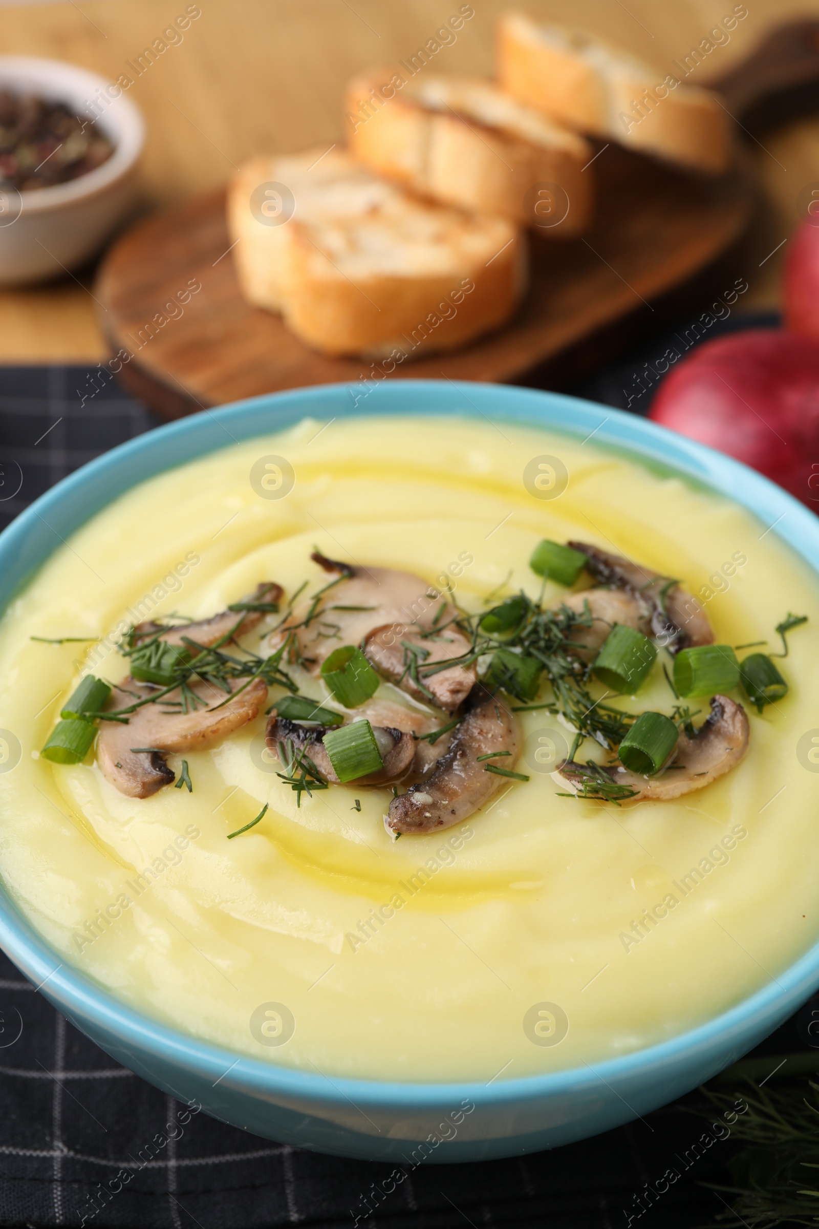 Photo of Bowl of tasty cream soup with mushrooms, green onions and dill on table, closeup