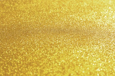 Photo of Beautiful golden shiny glitter as background, closeup