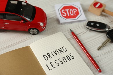 Composition with workbook for driving lessons and toy car on white wooden background. Passing license exam