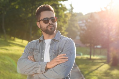 Handsome man wearing sunglasses in park, space for text