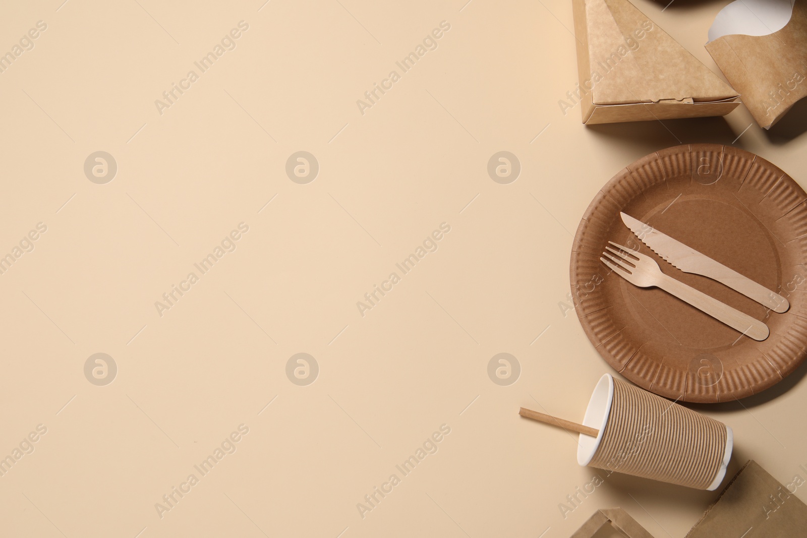 Photo of Eco friendly food packaging. Paper containers and tableware on beige background, flat lay. Space for text