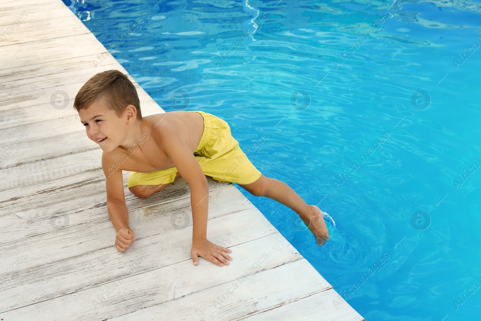 Photo of Little child near outdoor swimming pool. Dangerous situation