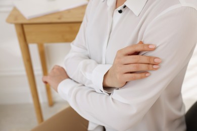 Photo of Woman touching shirt made of smooth white fabric indoors, closeup