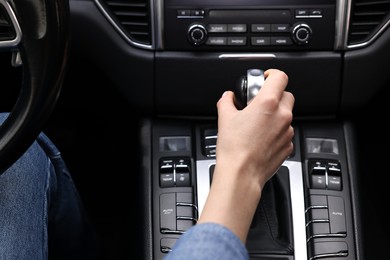 Woman using gear stick while driving her car, closeup