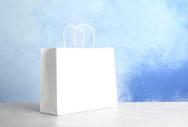 Photo of Mockup of paper shopping bag on table against color background