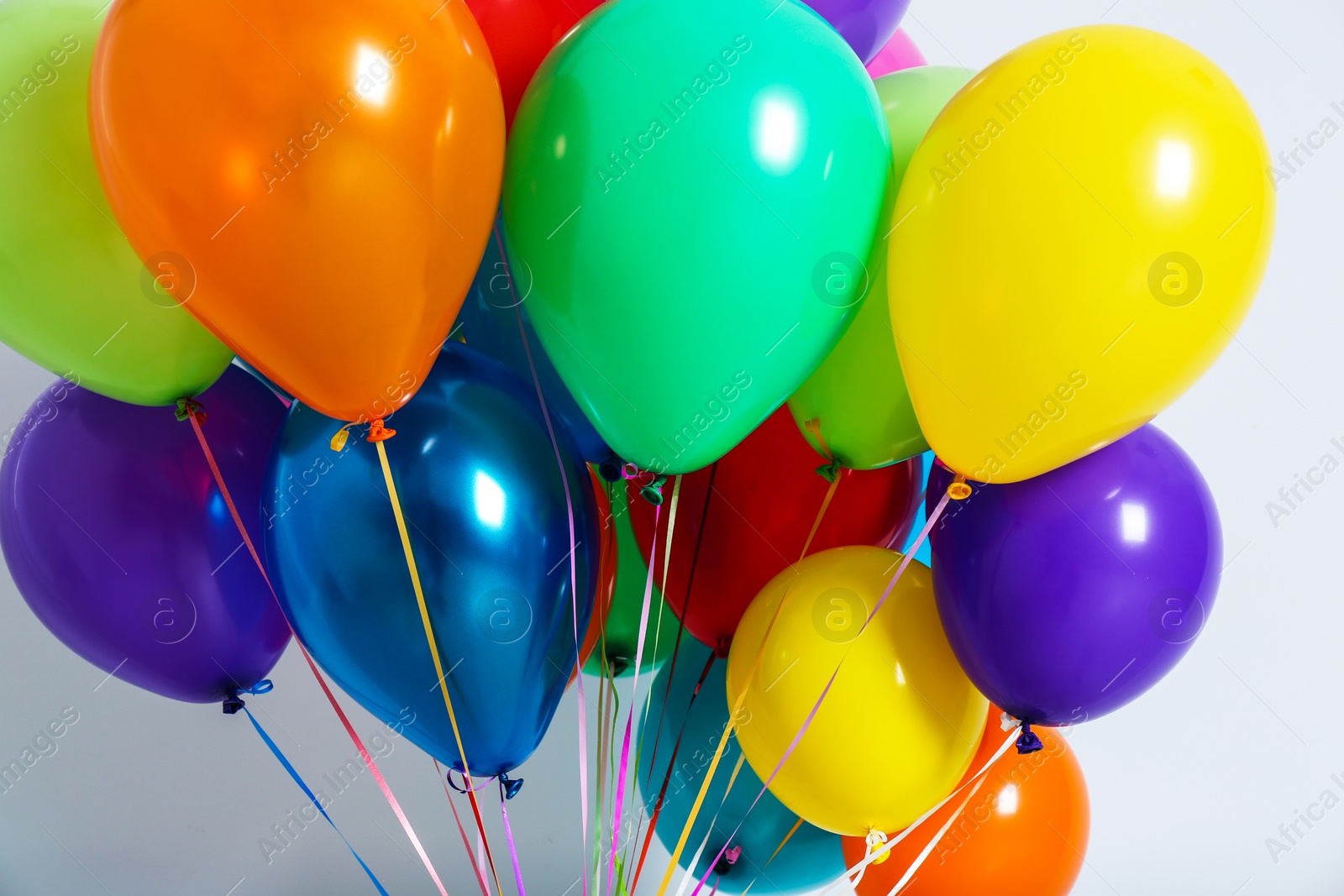 Photo of Bunch of colorful balloons on white background, closeup. Festive decor