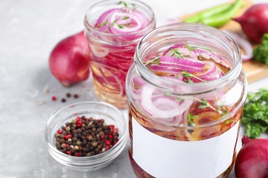 Photo of Jars of pickled onions on marble table, closeup