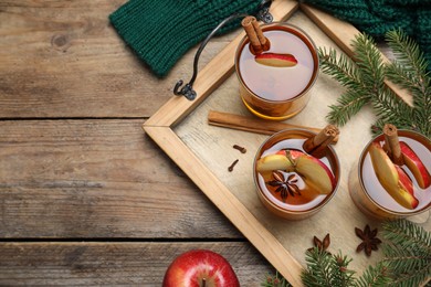 Hot mulled cider, ingredients and fir branches on wooden table, flat lay. Space for text