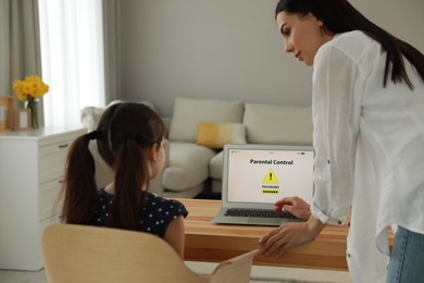 Mother installing parental control app on laptop to ensure her child's safety at home