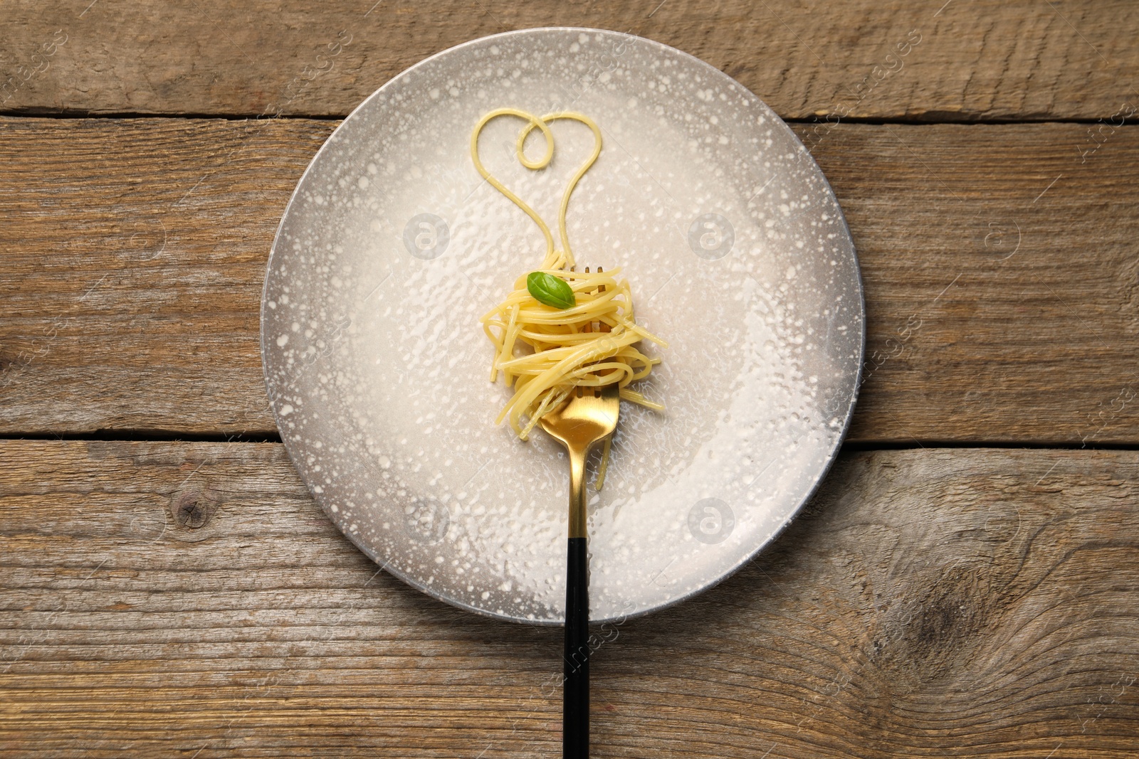 Photo of Heart made with spaghetti and fork on wooden table, top view
