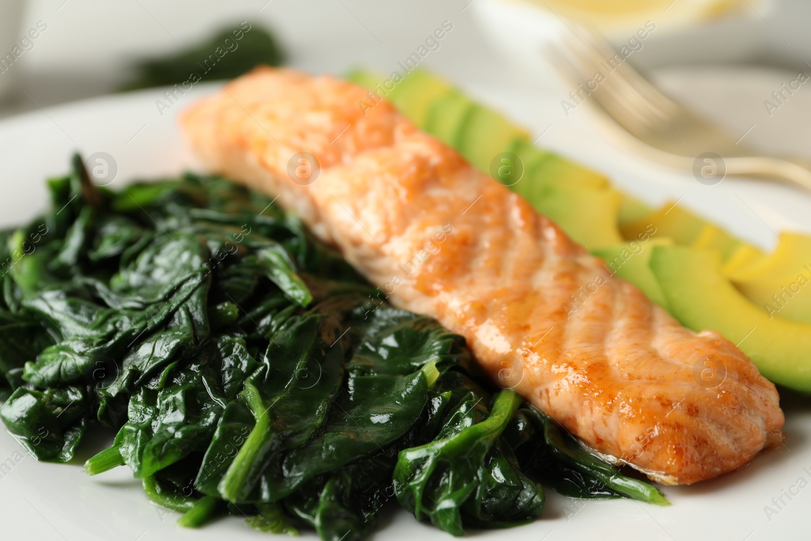 Photo of Tasty salmon with spinach and avocado on plate, closeup