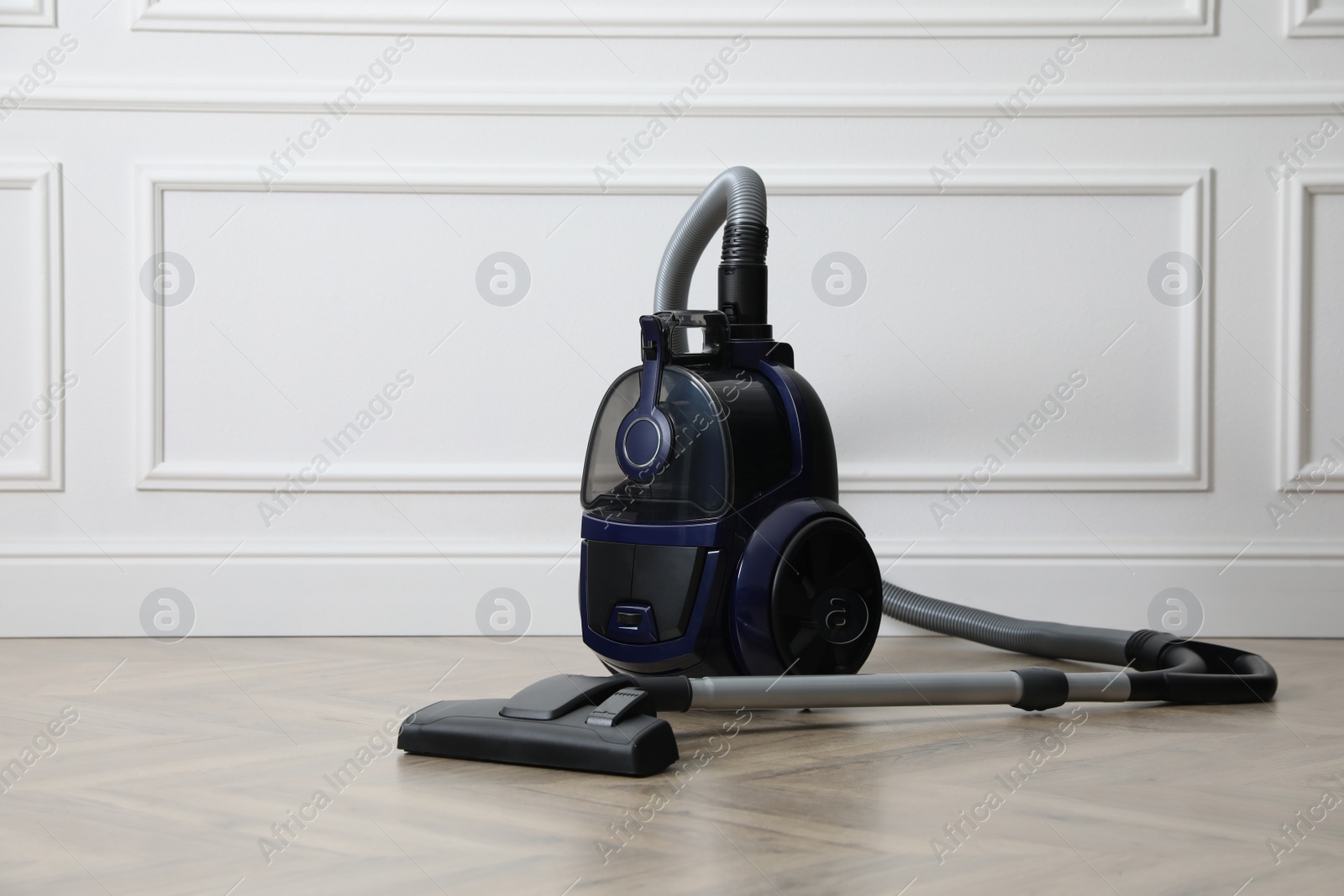 Photo of Modern vacuum cleaner near white wall indoors