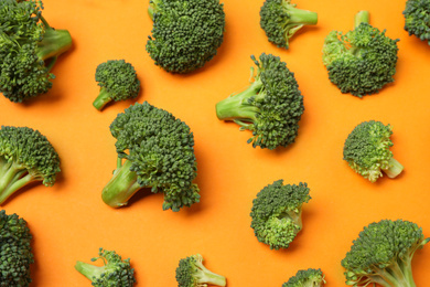 Fresh tasty broccoli on orange background, flat lay