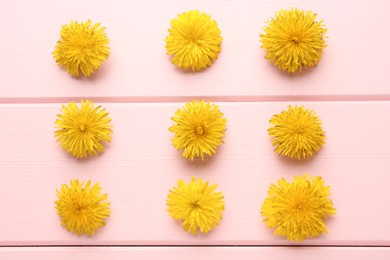 Photo of Flat lay composition with beautiful yellow dandelions on pink wooden table