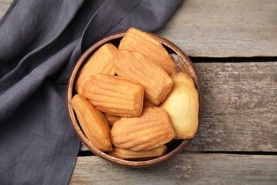 Photo of Tasty madeleine cookies in bowl on wooden table, top view