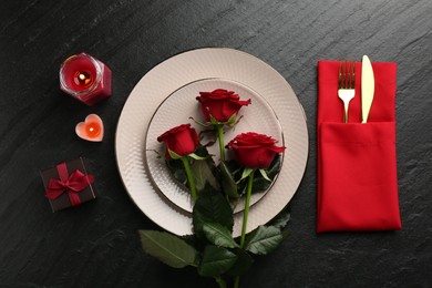 Photo of Place setting with candles, gift box and roses on grey textured table, flat lay. Romantic dinner