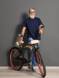 Photo of Portrait of handsome mature man with bicycle near color wall