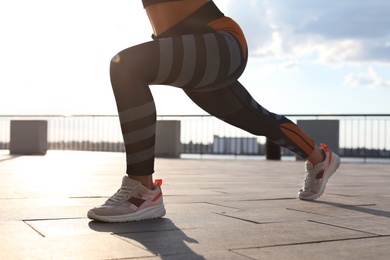 Photo of Young woman doing exercise outdoors in morning, closeup