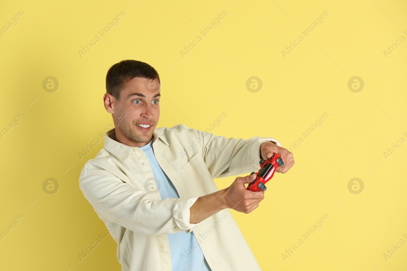 Photo of Happy man playing video games with controller on yellow background